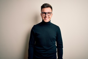 Fototapeta premium Young handsome caucasian man wearing glasses and casual sweater over isolated background with a happy and cool smile on face. Lucky person.