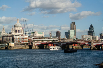 London city skyline with river, boats, bridge and clouds