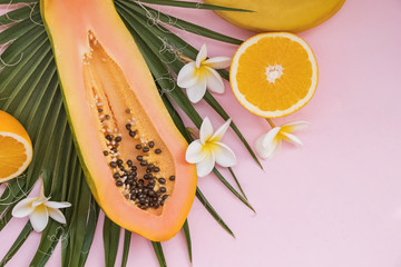 Creative composition with palm leaves, papaya and plumeria flowers.