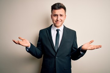 Young handsome business man wearing elegant suit and tie over isolated background clueless and...