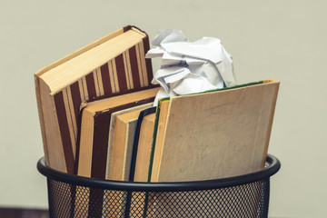 Books and crumpled paper in the bin. Books that do not read, low-grade literature