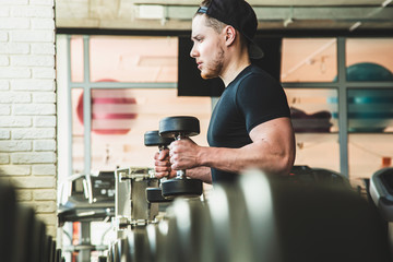 Portrait of a muscular man performs exercises in the gym. Strength training with dumbbells