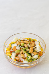 Salad with sliced avocado onions and canned corn in the bowl with copy space
