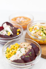 Fototapeta na wymiar Mixed salads with avocado corn beans beet and onions in bowls