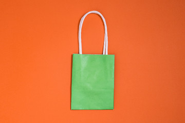 Paper bag with white handles on an orange background. Bag for delivering food from a store or cafe....