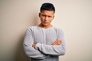Young handsome latin man wearing casual sweater standing over isolated white background skeptic and...