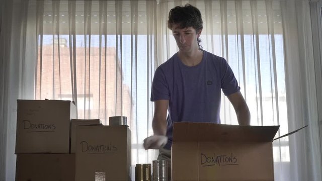 Man preparing box of donations with canned food