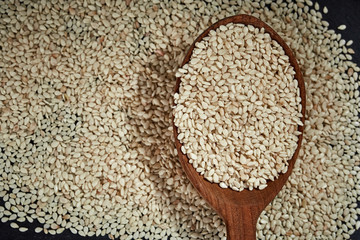 Sesame seeds and a wooden spoon on a dark table. Healthy food and drink concept. Top View.