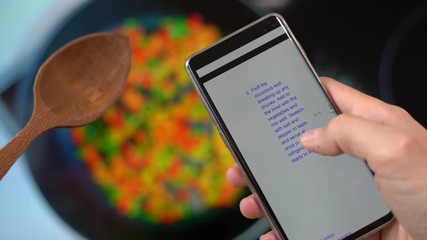 Man uses sliding finger on phone screen preparing to cook, following cooking recipe online. Cooking from home and modern lifestyle concept