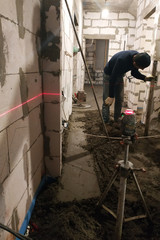 In the newly built house the worker performs a sand-cement screed for heating.