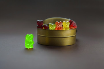 One gummy bear stands apart from a group of other jelly bears sharing the same candy jar....