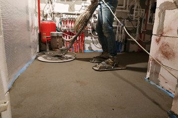 The worker with special tools performs sand-cement screed for heating and floor heating.