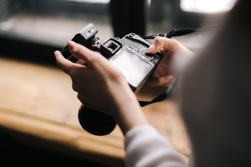 Close-up of woman hands holding professional DSLR camera and looking screen, Concept of creative work in photo studio.