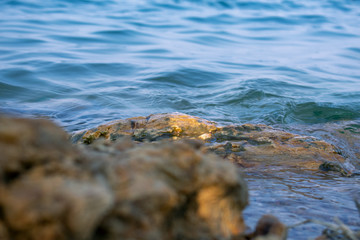 small waves cutting the rocks in the shore of a blue lake