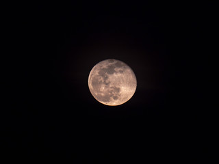 A detailed close up of a full moon centered in frame on a black night sky background.