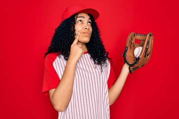 Young african american curly sportswoman wearing cap playing baseball using ball and glove serious...