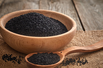 Black cumin seeds and a wooden spoon on a wooden table. Healthy, vegetarian, organic food concept.