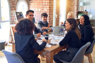 Group of business workers smiling happy and confident. Working together with smile on face  using laptop and speaking at the office