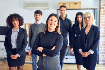 Group of business workers smiling happy and confident. Posing together with smile on face looking at the camera, young beautiful woman with crossed arms at the office