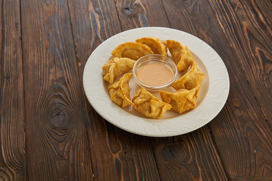 Yaki gedza japanese dumplings with sauce in white plate on dark wooden table