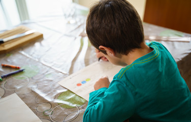 child drawing with crayons on paper or doing homework from home. Home schooling or e-learning...