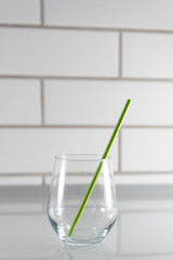 transparent empty glass with green paper drinking straw in the kitchen