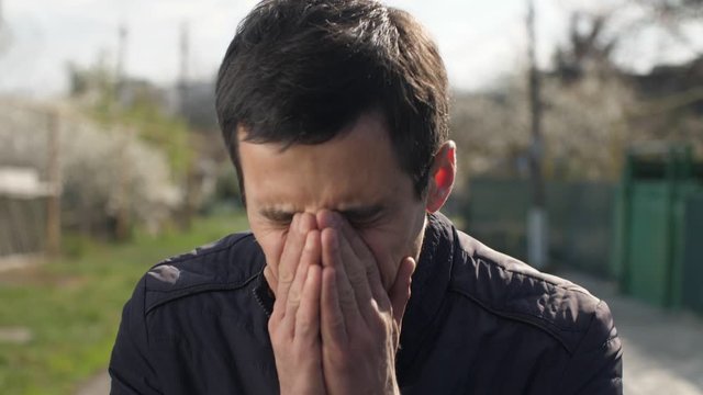 Funny man sneezing on the street