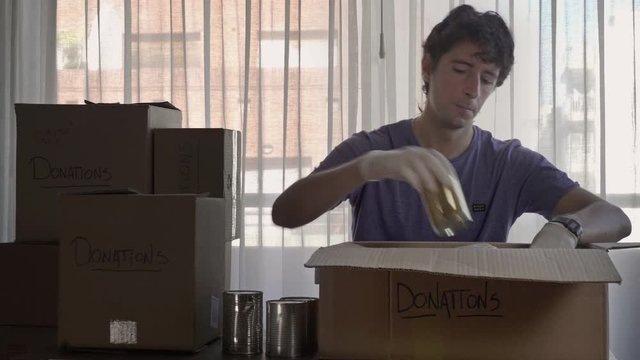 Man preparing box of donations with canned food