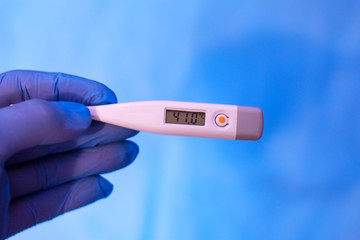 Obraz premium high temperature electronic thermometer in hand with glove.