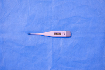 electronic thermometer lies on a blue background.