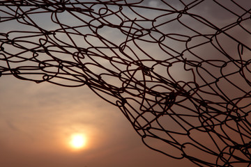Sunset through barbed wire shows overcome difficulties, freedom and achievement concepts
