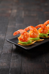 shrimps served on nacho chips with guacamole