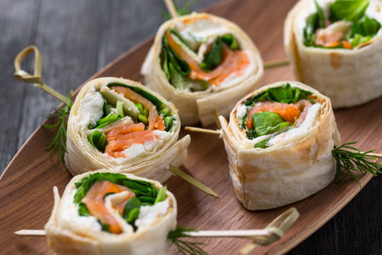 tortilla rolls with salmon, cream cheese and salad, catering snacks, finger food