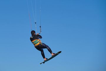 Kitesurfer in wetsuit in  the jump on a background of blue sky