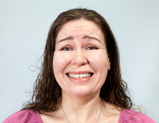 Uncertainty and embarrassment on the face of an adult woman, portrait on grey background, emotions...