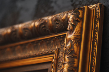 Beautiful golden frame on black wall with pattern close up