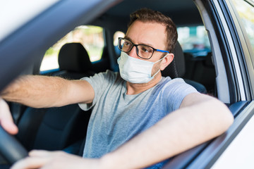 Portrait of man wearing surgical mask while driving a car.