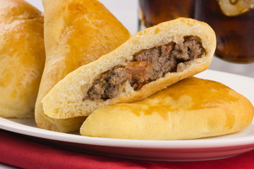 Syrian-Lebanese pie stuffed with meat called sfiha with one open in a platter in white background close