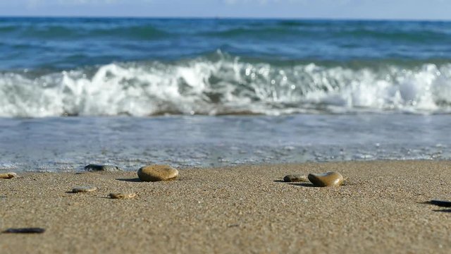 Sandy sea beach with pebbles and foam of the waves in motion, UHD