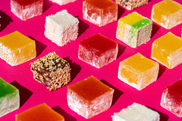Turkish delight square pieces on a bright pink background close up