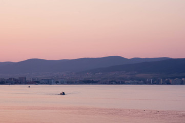 a ship against the background of mountains sails to the pier at sunset