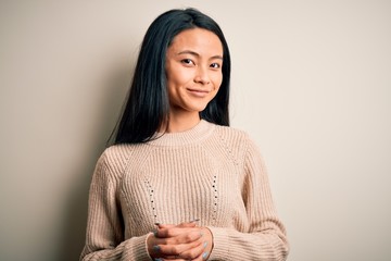 Young beautiful chinese woman wearing casual sweater over isolated white background with hands together and crossed fingers smiling relaxed and cheerful. Success and optimistic