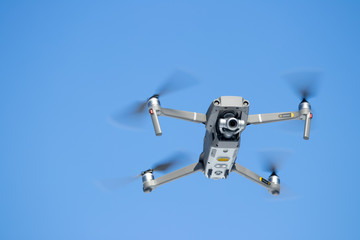 Looking Up at a Quad Copter Drone In Flight against a blue sky