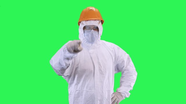 A man in a helmet and protective suit picks out his hand.Green screen background.