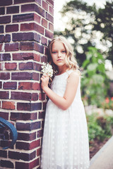 Fashion portrait of beautiful 9 -10 years old girl wearing white dress and posing in park.