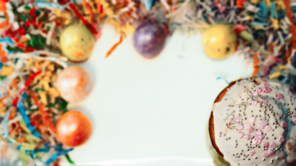 Colorful Easter eggs on stands, with paper decor of different colors in focus. Cake with icing in focus. 
With free space.