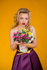 Long-haired girl, blonde hair, blonde on a yellow, green background in the studio, pin-up style. Red lips, short dress, shorts and a red shirt. Sexy girl

