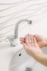 Woman washes her hands by surgical hand washing method. She washes his hands for at least 20 seconds. Focuses on her hands.