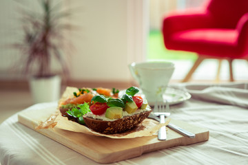 Wholegrain toast with avocado, tomato and salmon on wooden cutting board