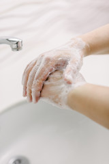 Woman washes her hands by surgical hand washing method. She washes his hands for at least 20 seconds. She washes between his fingers and his hands.